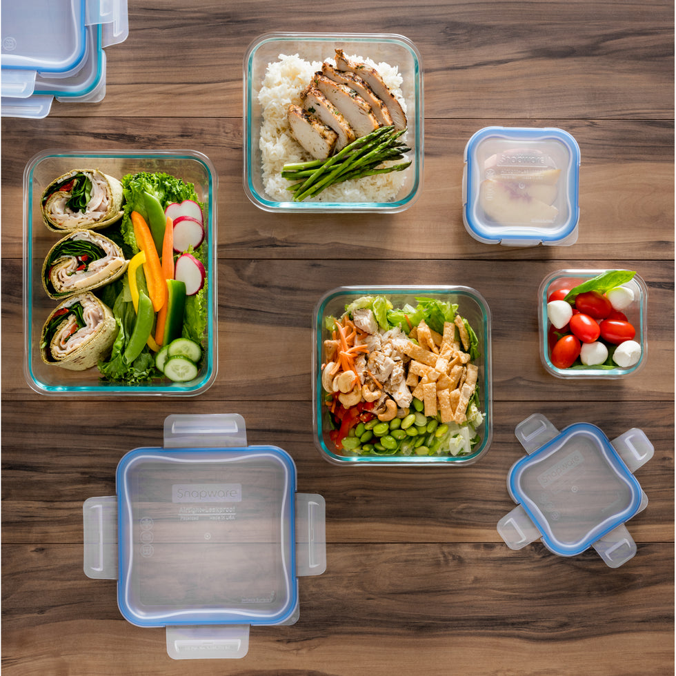 Glass meal prep containers with food on a wooden table.