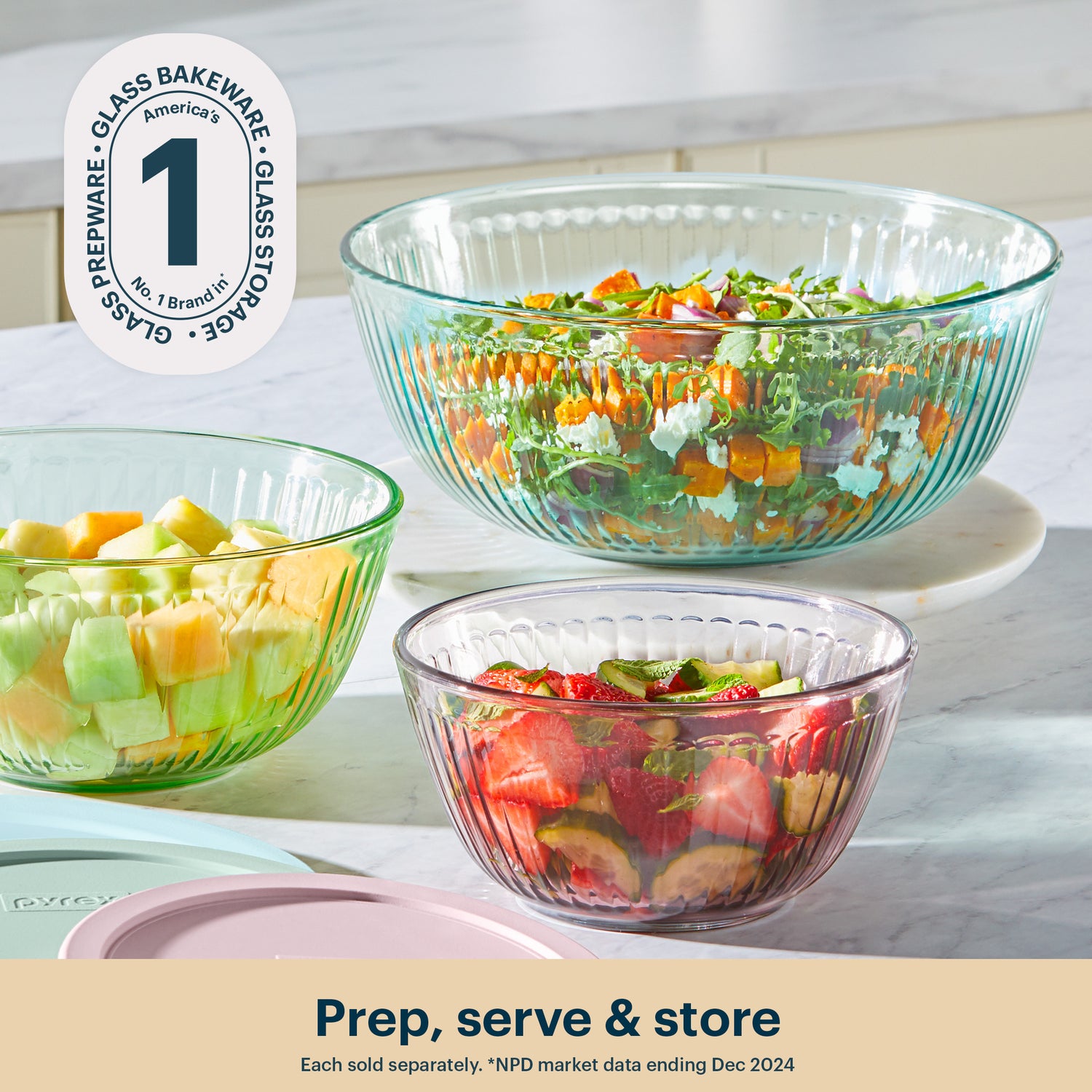 Three glass bowls with salad on a kitchen counter, featuring the Pyrex brand.
