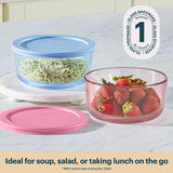 Glass food storage containers with lids containing rice and strawberries on a white surface.