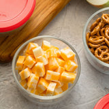 Bowl of cheese cubes next to a bowl of pretzels on a gray surface.