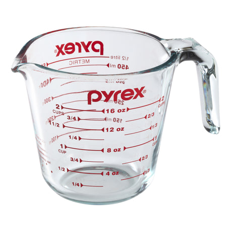 Pyrex measuring cup with red measurement markings on a white background
